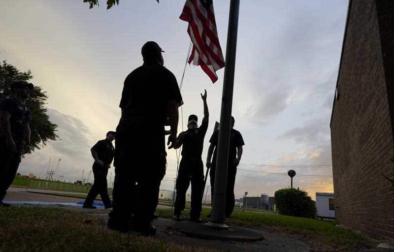Port Arthur firefighters lower a US flag at a post office at sunset as they wait for Hurricane Laura to make landfall