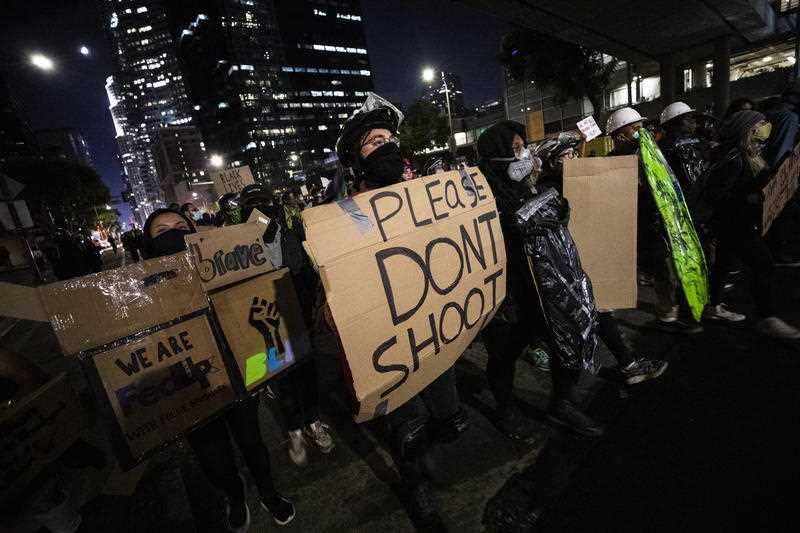  A protester holds a makeshift shield as around a hundred protesters gather during a protest in Los Angeles.