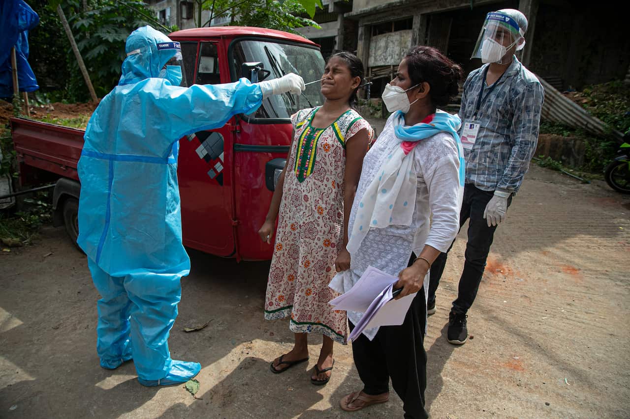 An Indian health worker takes a nasal swab sample to test for COVID-19 during a door to door test drive in Gauhati, India.