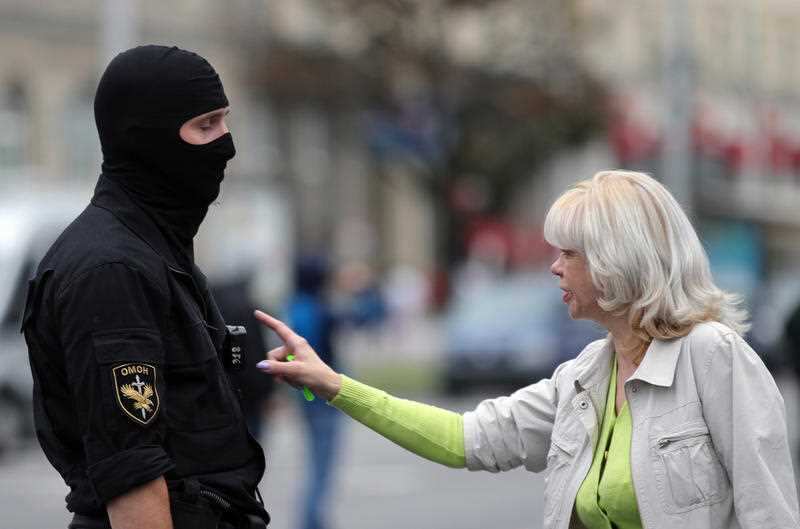 Opposition activists talk to a law enforcement officer during a women's rally.