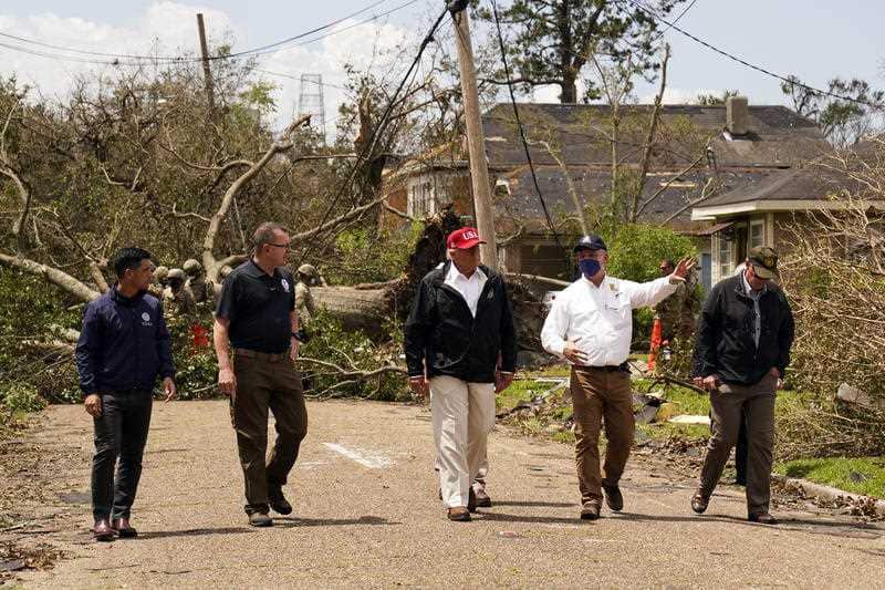 President Donald Trump listens to Louisiana Governor John Bel Edwards, centre, as he tours damage from Hurricane Laura,