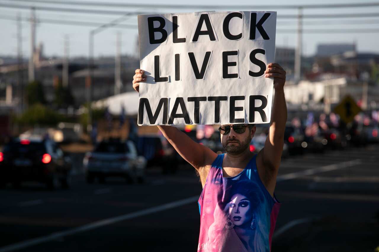 A Black Lives Matter supporter holds a sign as supporters of President Donald Trump attend a rally and car parade in Portland, Oregon.