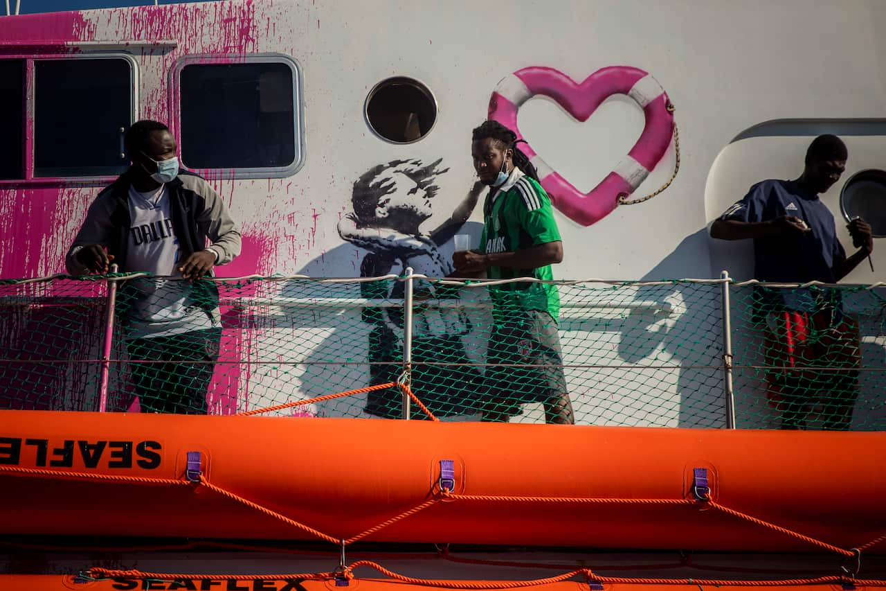 A man passes by a painting by British artist Banksy on the deck of the Louise Michele rescue vessel, after performing 2 rescue operations.