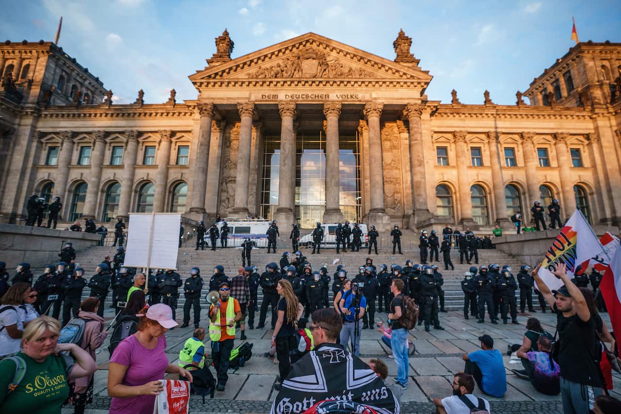 Riot police monitor right-wing protesters in front of the Reichstag building.