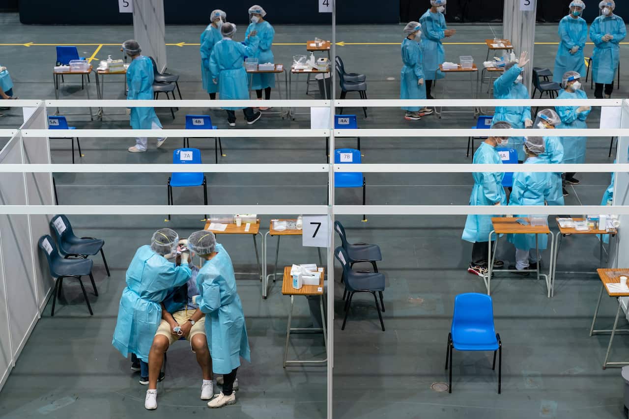 Medical professionals collect samples from a man at a makeshift COVID-19 testing site at Queen Elizabeth Stadium in Hong Kong on 1 September.