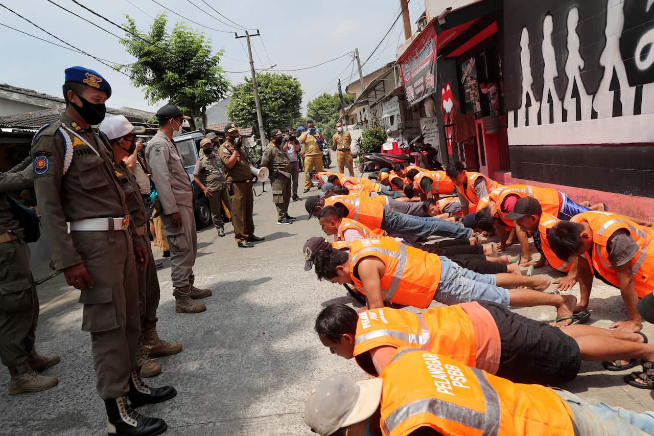 Public Order Agency officers watch people caught without masks do push ups in Tangerang on the outskirts of Jakarta.