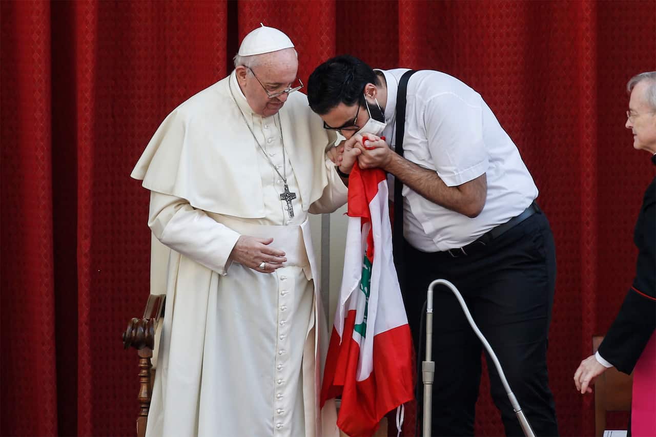 A person kisses Pope Francis' hand while holding he Lebanese flag on 2 September.