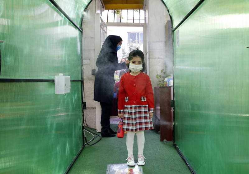  An Iranian elementary school girl wearing a face mask passes by a disinfection tunnel as she attends the first day of reopening the Bamdad Parsi private school, north of Tehran, Iran, 05 September 2020