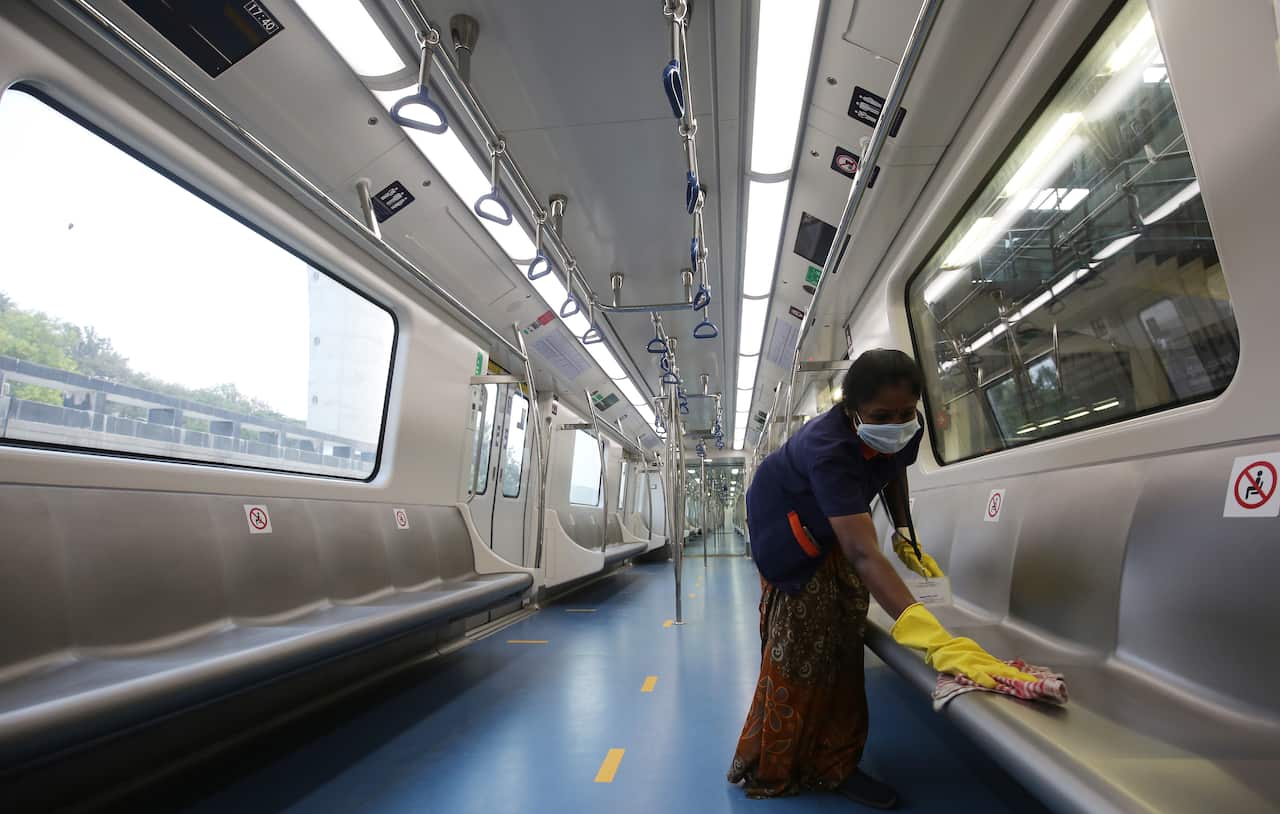 A rail worker cleans a train seat as Metro services in Bangalore resume.