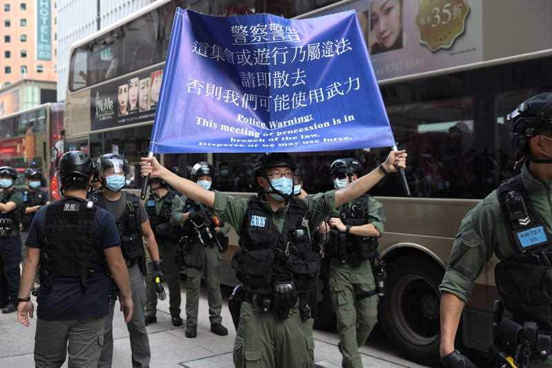 A police officer holds up a flag warning protesters to disperse