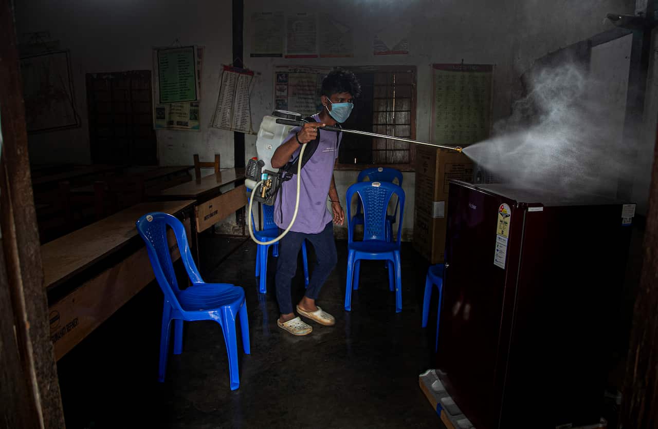 An Indian health worker disinfects a COVID-19 test center in Gauhati, India.