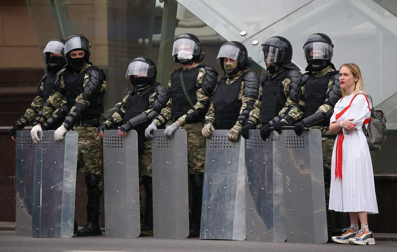An opposition supporter stands next to riot police officers blocking Independence Avenue during the March of Unity.