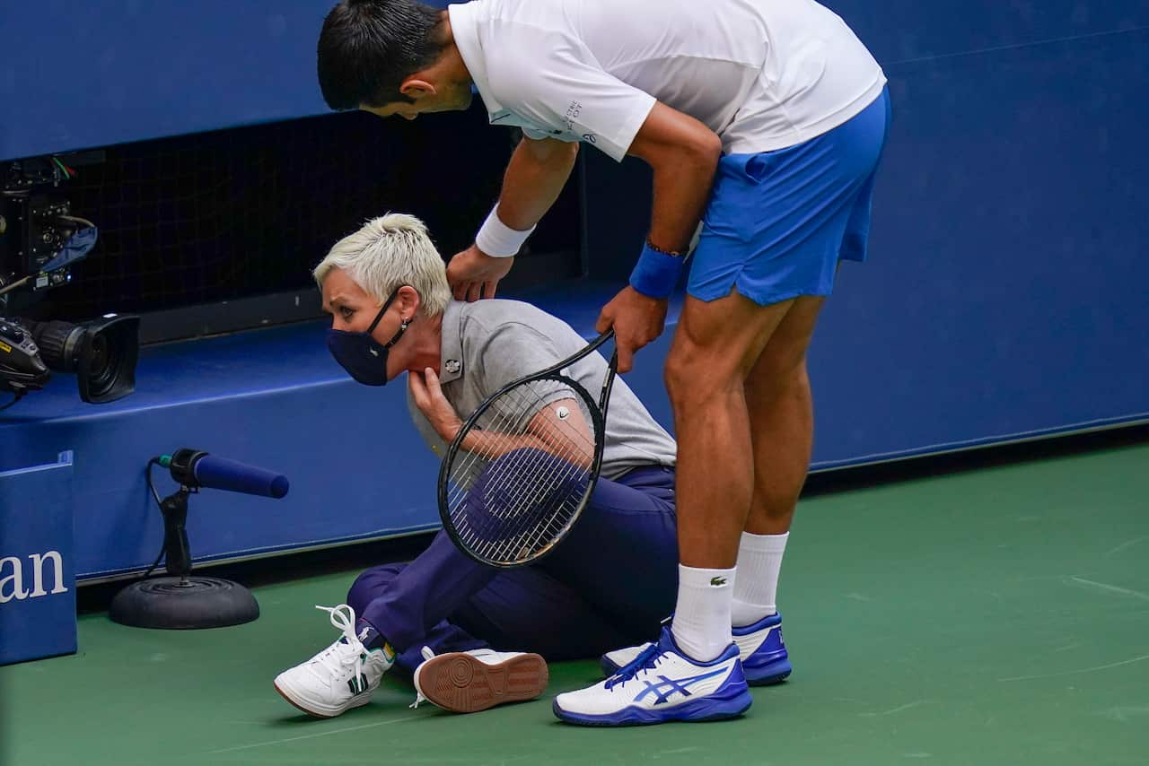 Novak Djokovic checks on a lineswoman after hitting her with a ball in reaction to losing a point to Pablo Carreno Busta, of Spain during the US Open.