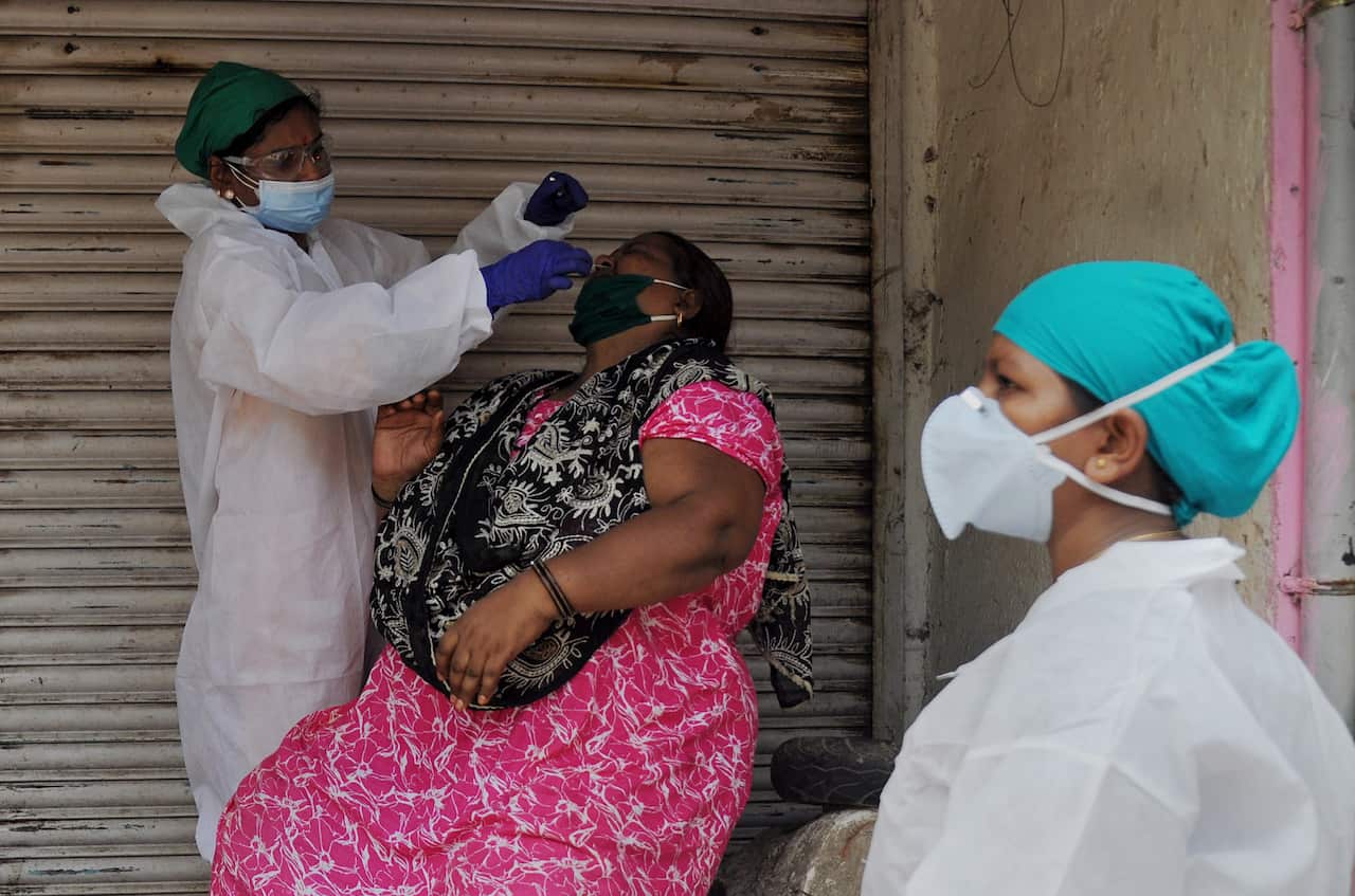 Healthcare worker collects a nasal swab from a woman in Mumbai.