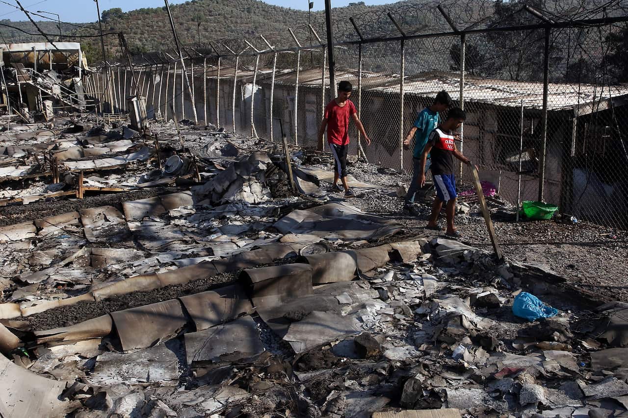 Young asylum seekers walk among debris in the Moria refugees camp.
