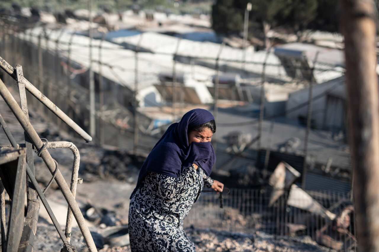 A woman walks among the rubble in the Moria refugee camp after a fire.