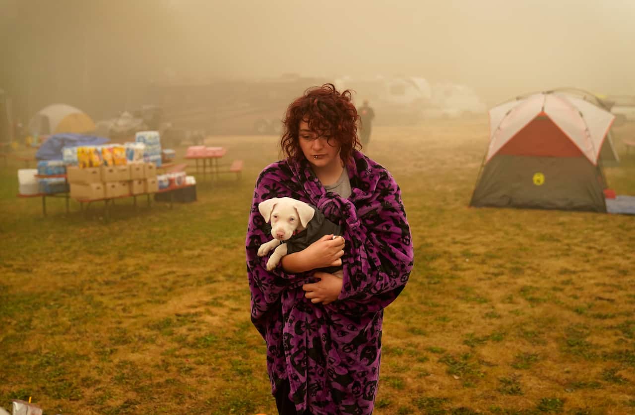 A woman holds her dog after several days of staying in a tent at an evacuation center at the Milwaukie-Portland Elks Lodge in Oak Grove, Ore.