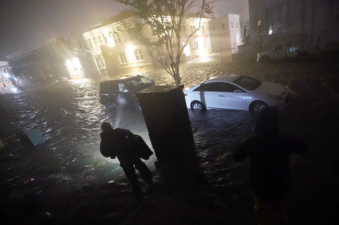 People use flashlights as they walk on flooded streets in search of their vehicle in Pensacola on 16 September 2020. 
