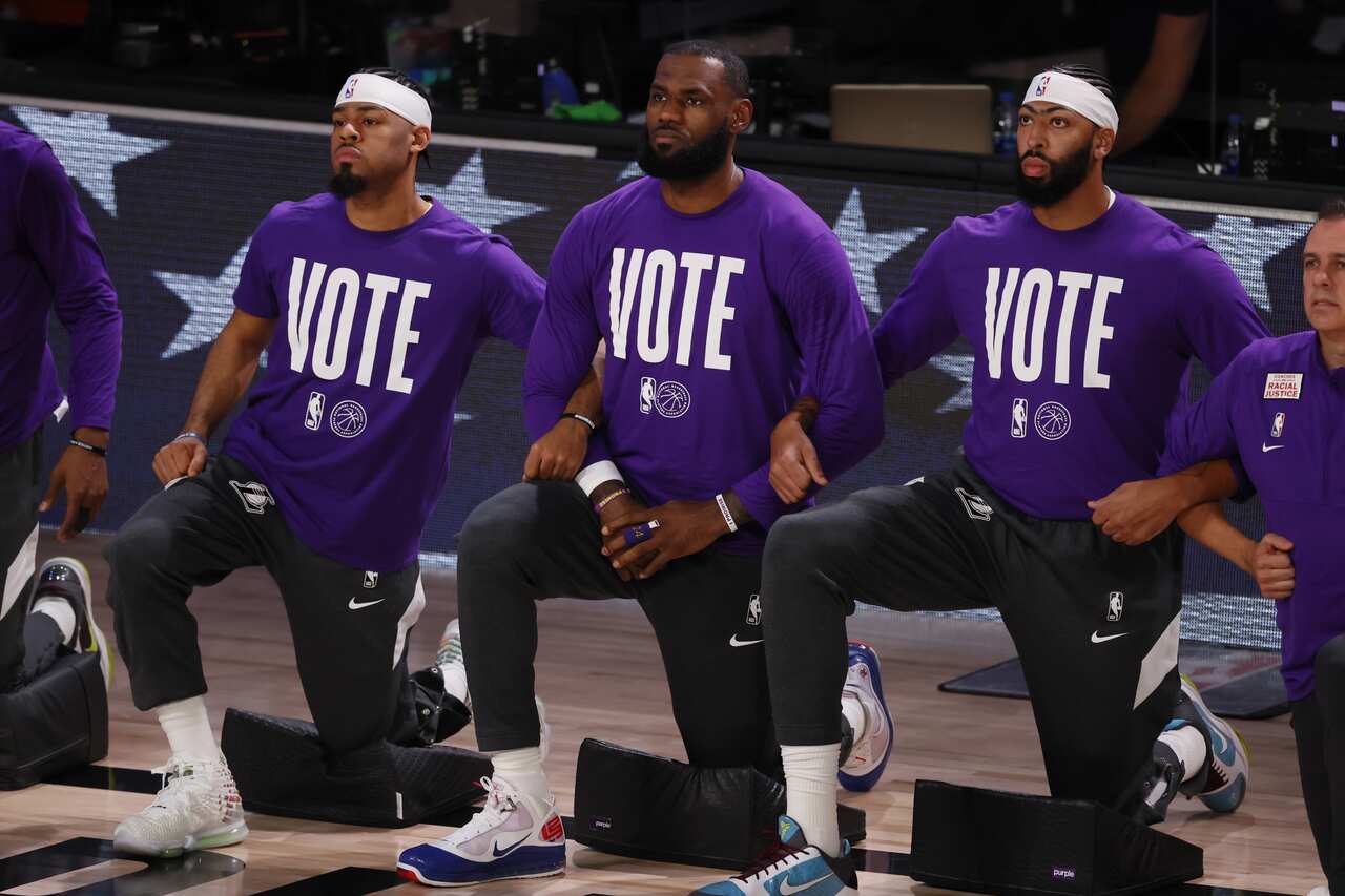 The Los Angeles Lakers LeBron James (C), Quinn Cook (L) and Anthony Davis take a knee during the national anthem while wearing their 'VOTE'  shirts. 