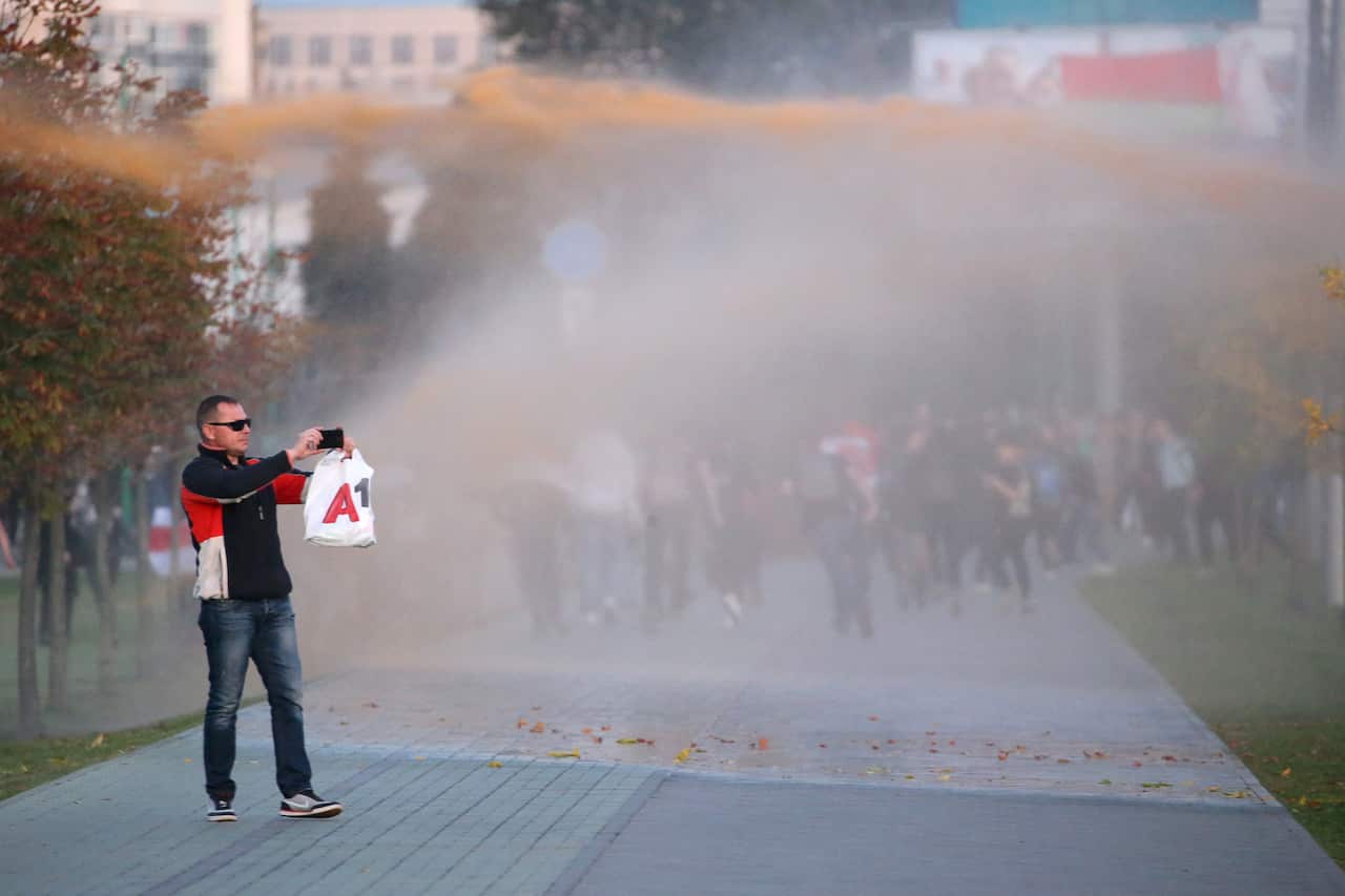 A participant in a protest against the inauguration of Alexander Lukashenko as Belarus' President takes a photograph of a water jet cannon by the Minsk