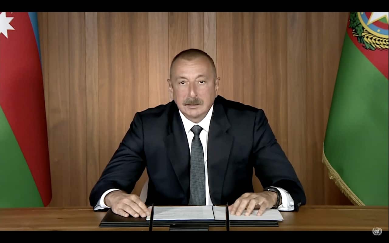 A man wearing a suit stares ahead as he rests his hands on the table.