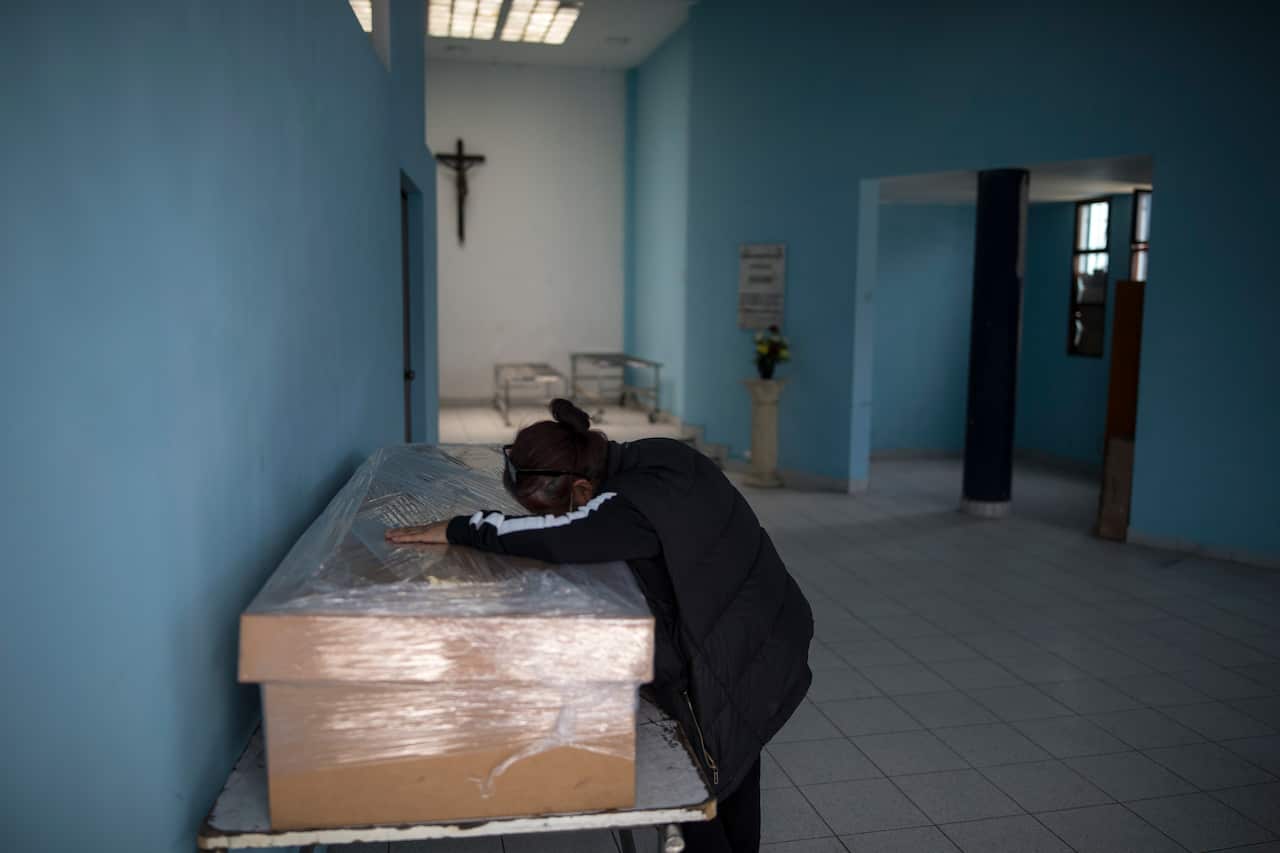 Elizabeth Alvarado cries over a cardboard coffin containing the body of her husband who died from COVID-19 complications, before his cremation in Lima, Peru.