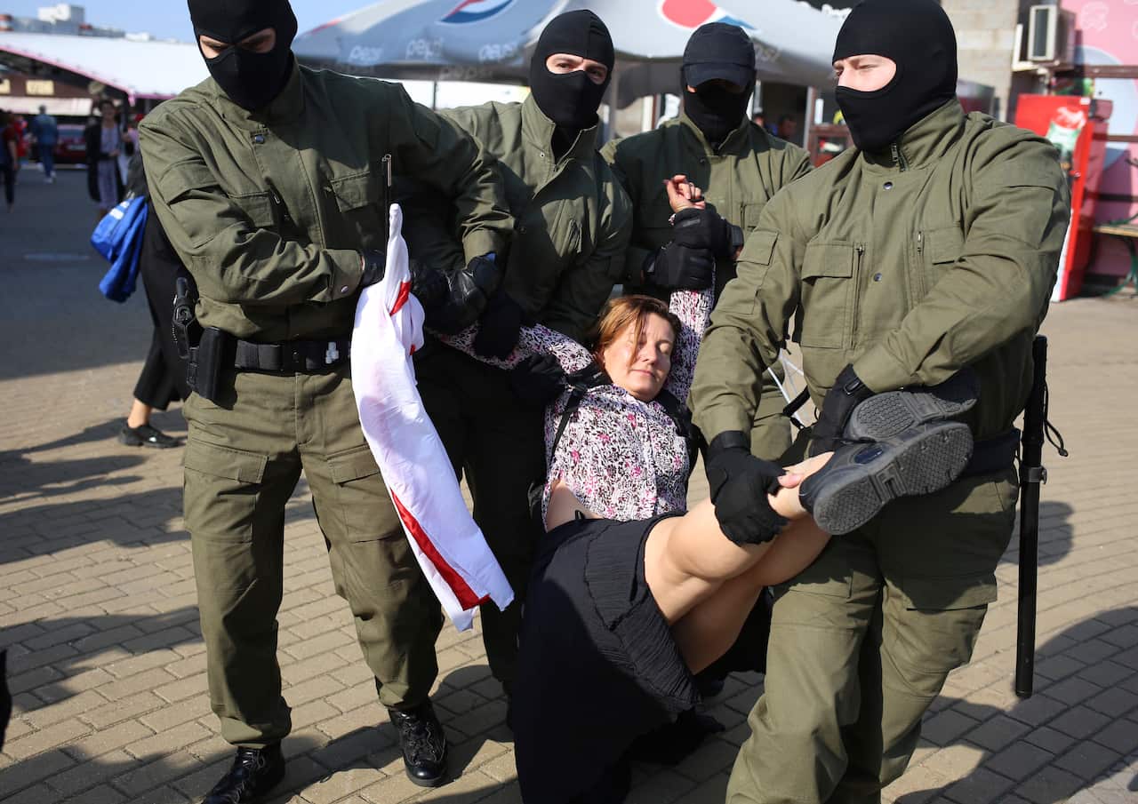 Police officer detain a woman during an opposition rally to protest the official presidential election results in Minsk on 26 September.