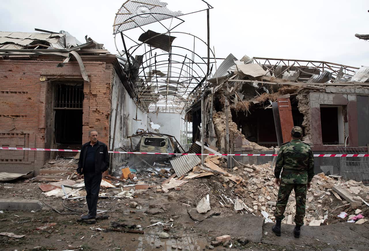 People look at destroyed buildings in a residential area in Ganja, Azerbaijan.