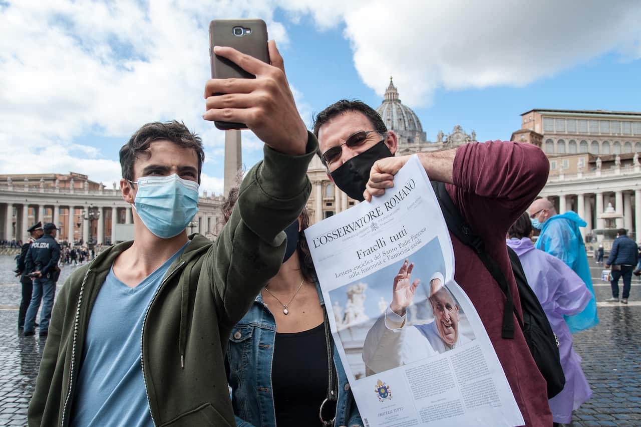 People pose with the paper in Peter's Square at the Vatican.