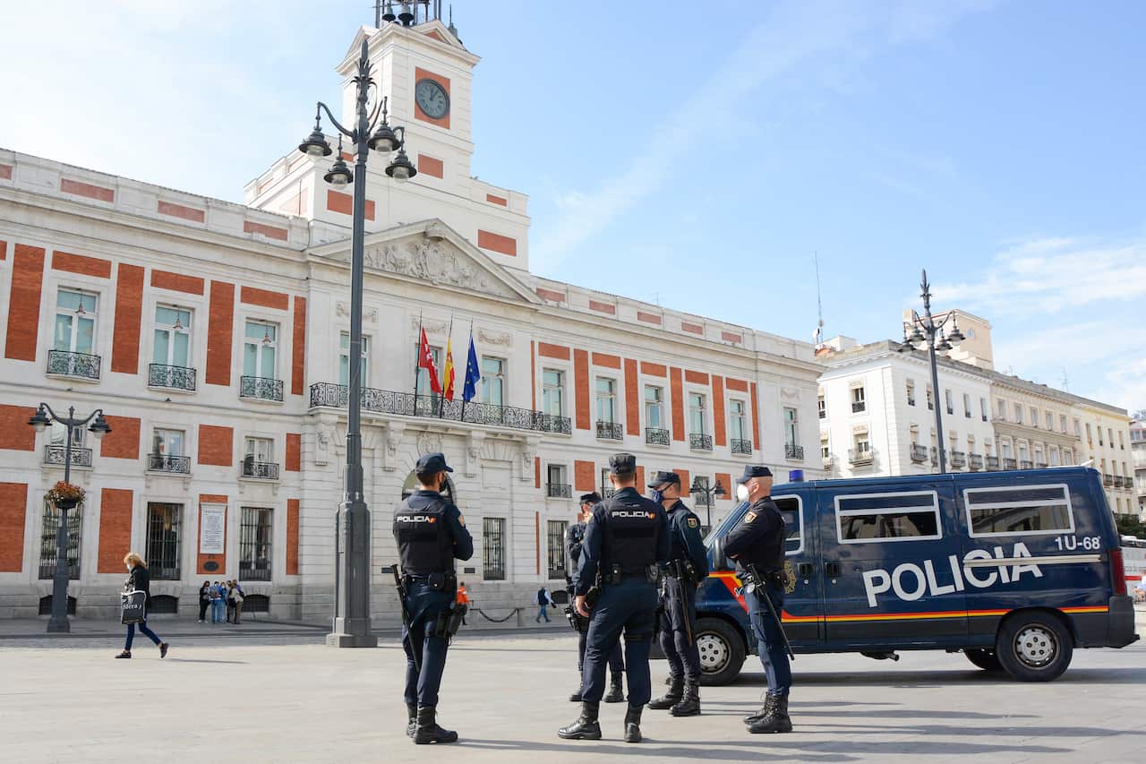 A group of police officers stand alert at Madrid's Puerta del Sol pictured empty.