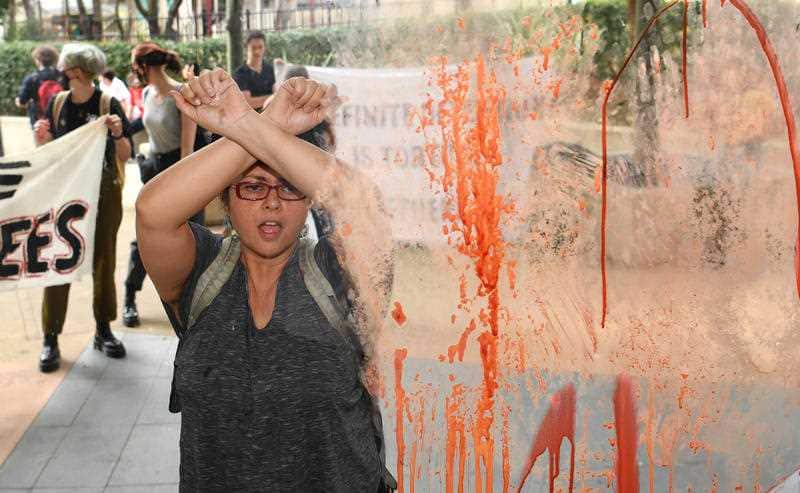 A refugee protester is seen outside a glass door