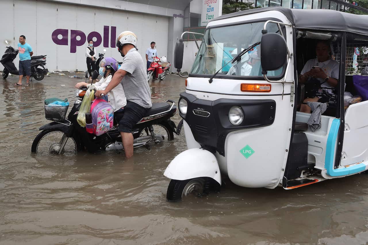 Local villagers travel through a flooded street following recent rains in Phnom Penh, Cambodia, on 12 October.