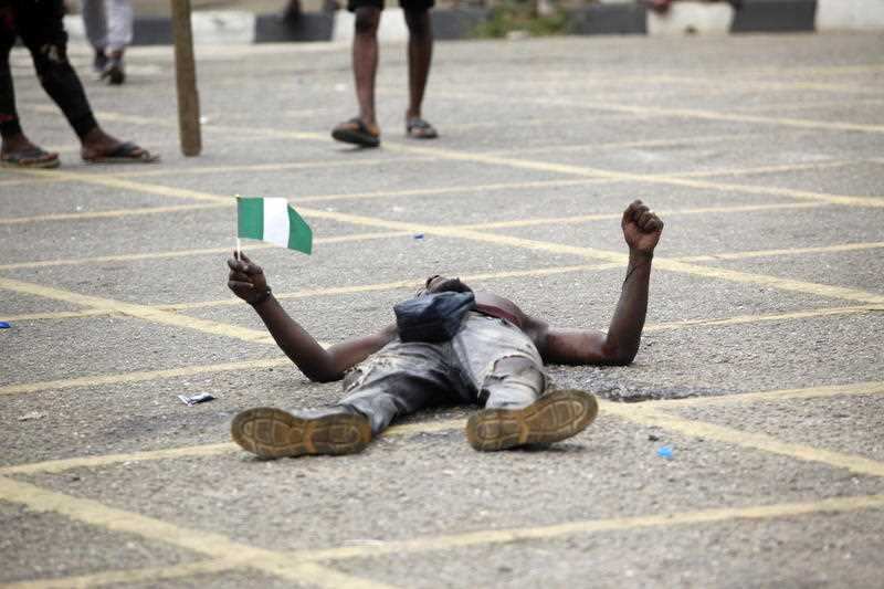 A protester holds the Nigerian flag in the Ikeja district of Lagos, Nigeria, 19 October 2020