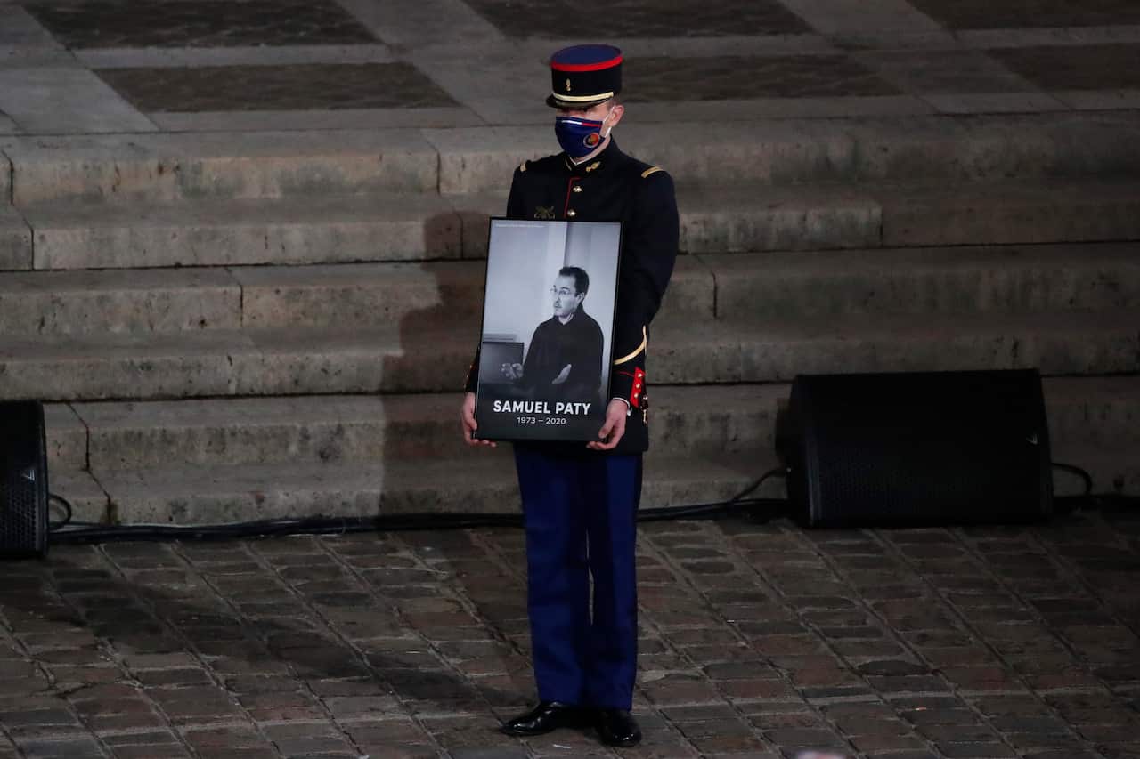  A Republican Guard holds a portrait of Samuel Paty in the courtyard of the Sorbonne university during a national memorial event, in Paris.