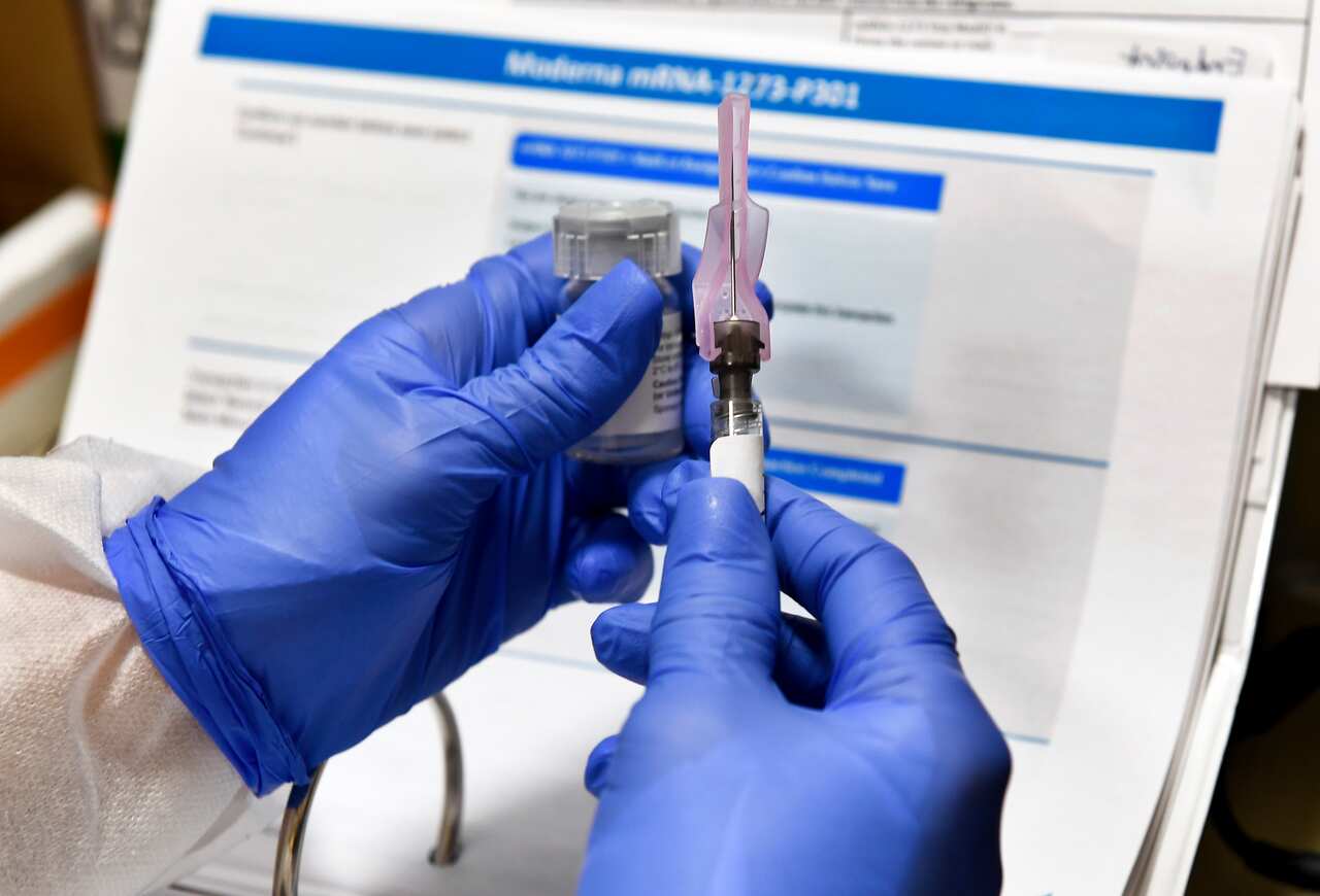 A nurse prepares an experimental vaccine for COVID-19 developed by the National Institutes of Health and Moderna Inc. at the United Health Services facility.