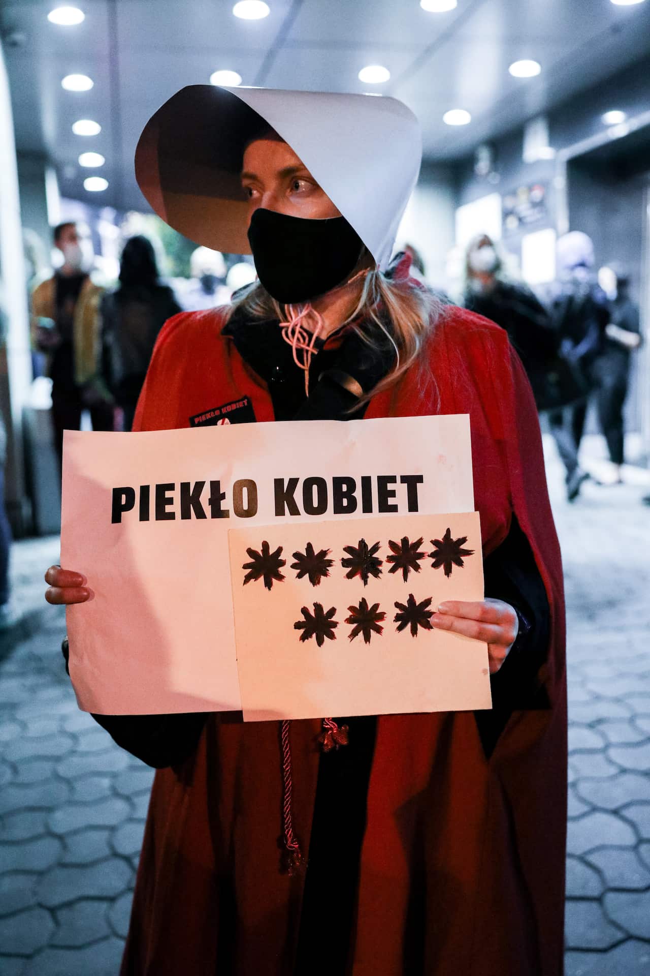 A protester dressed as a handmaiden holds a placard expressing her opinion during a demonstration in Poland.