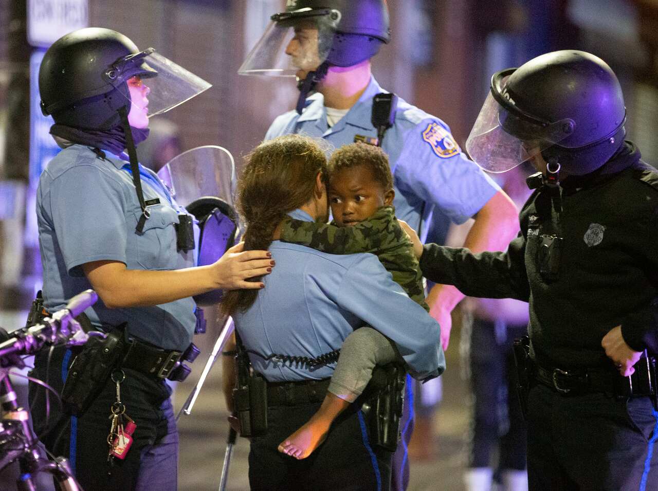 A police officer holds a young boy during a violent protest after police shot and killed a 27-year-old Black man on a Philadelphia street after yelling at him to drop his knife, Monday night, Oct. 26, 2020. (Charles Fox/The Philadelphia Inquirer via AP)