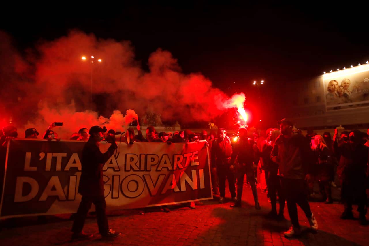 People light flares as they protest against the government restriction measures to curb the spread of COVID-19, in Rome Tuesday, Oct. 27, 2020. 