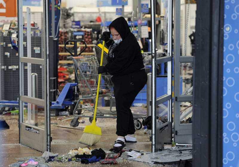 A woman cleans up debris at a Walmart, Wednesday, Oct. 28, 2020, that was damaged during protests in Philadelphia.