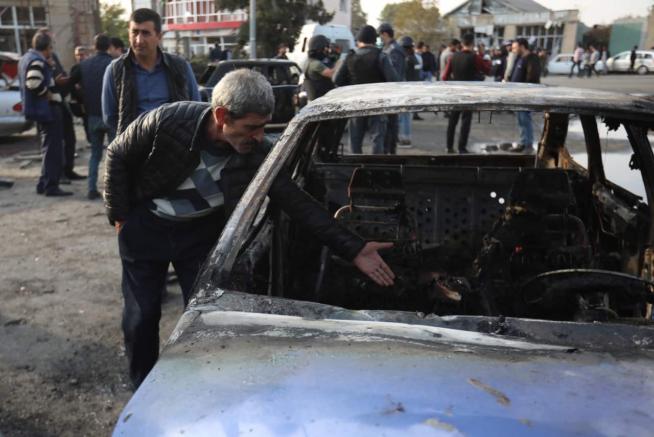 A man shows a burnt car after recent allegedly Armenian shelling in the town of Barda, Azerbaijan, on 28 October. 