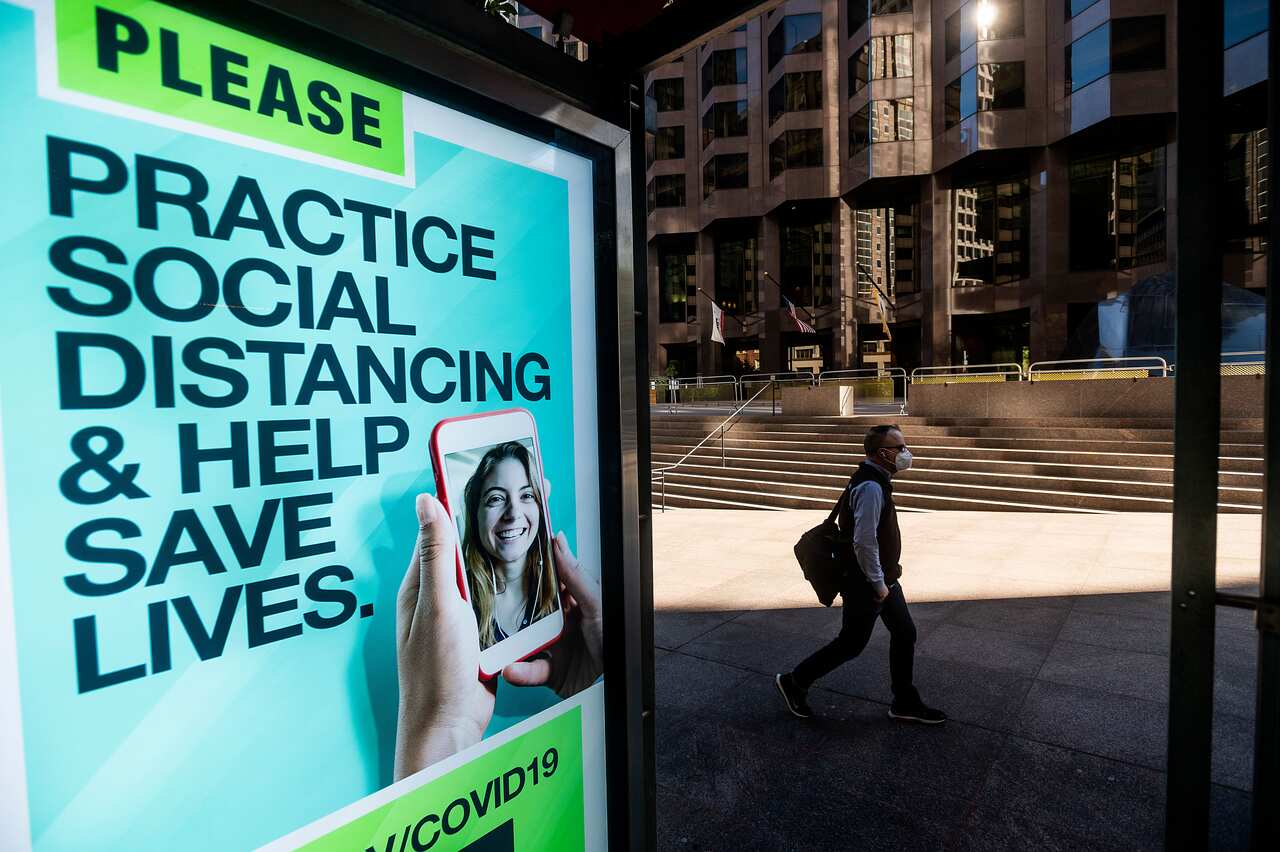 A man passes a COVID-19 public service notice in San Francisco's financial district on Wednesday, Oct. 21, 2020. 