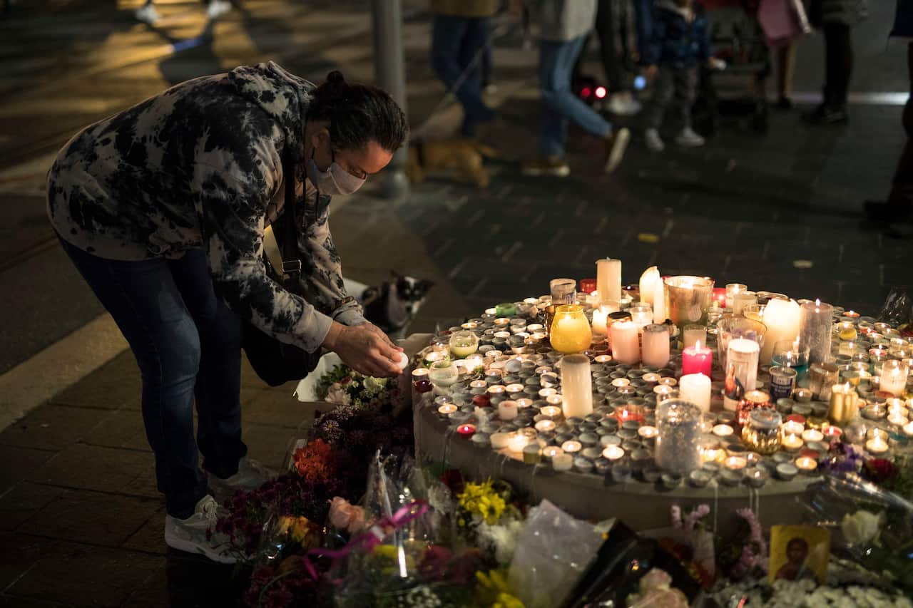 A man lights a candle in front of the Notre Dame church in Nice, France, Friday, Oct. 30, 2020.