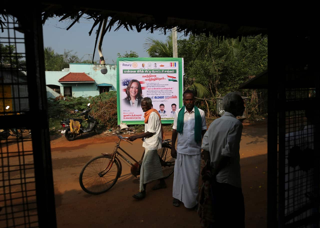 Villagers next to a billboard featuring US democratic vice presidential candidate Kamala Harris in Thulasendrapuram village, India.