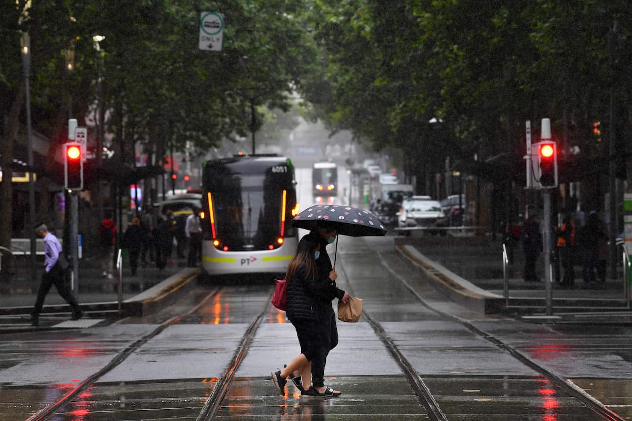 A person is seen walking across a street in the rain in Melbourne