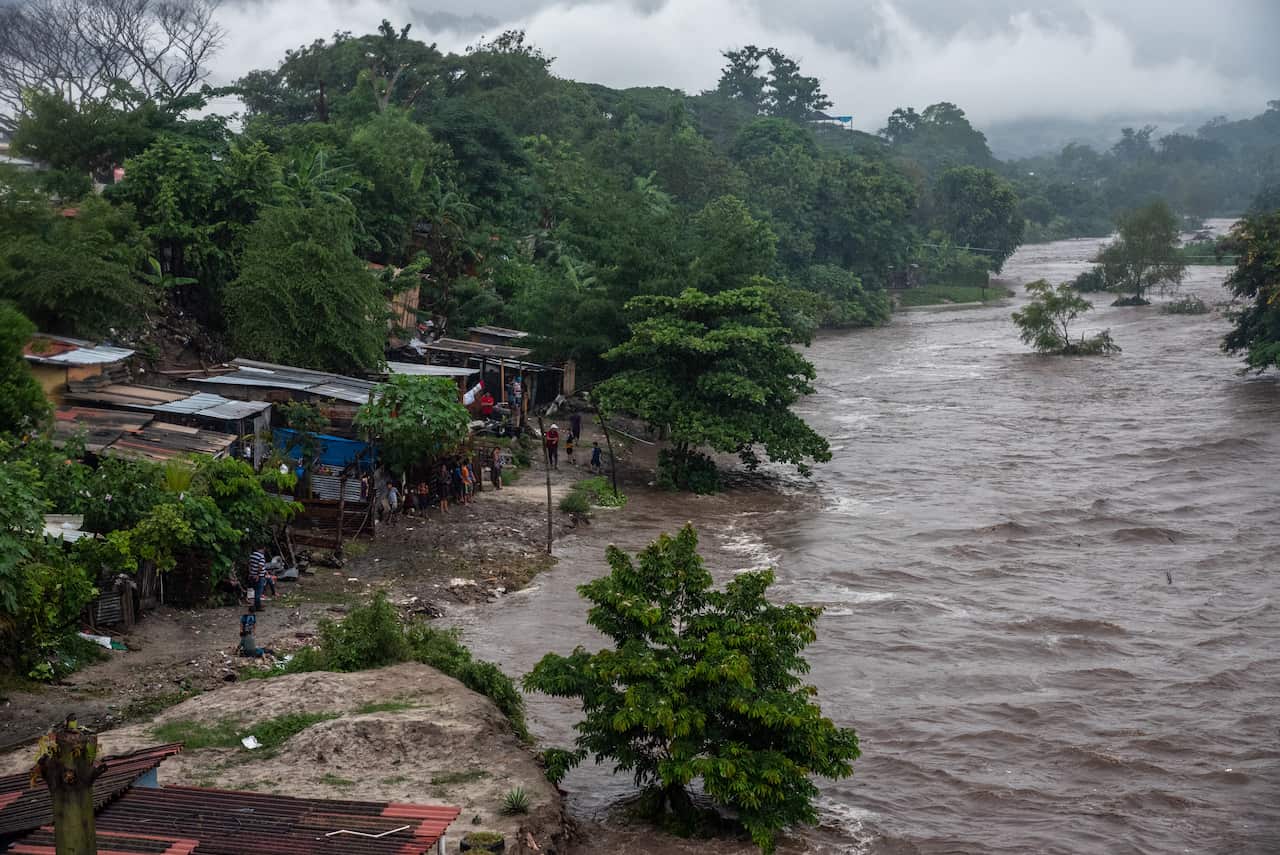 A cluster of shanty homes along the overflowing riverbank of Rio Blanco, Honduras, during the aftermath.