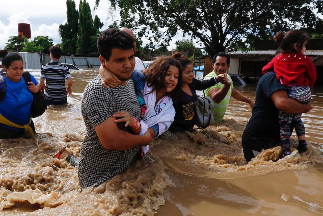 Residents wade through a flooded road, in Jerusalen, Honduras, on 5 November.