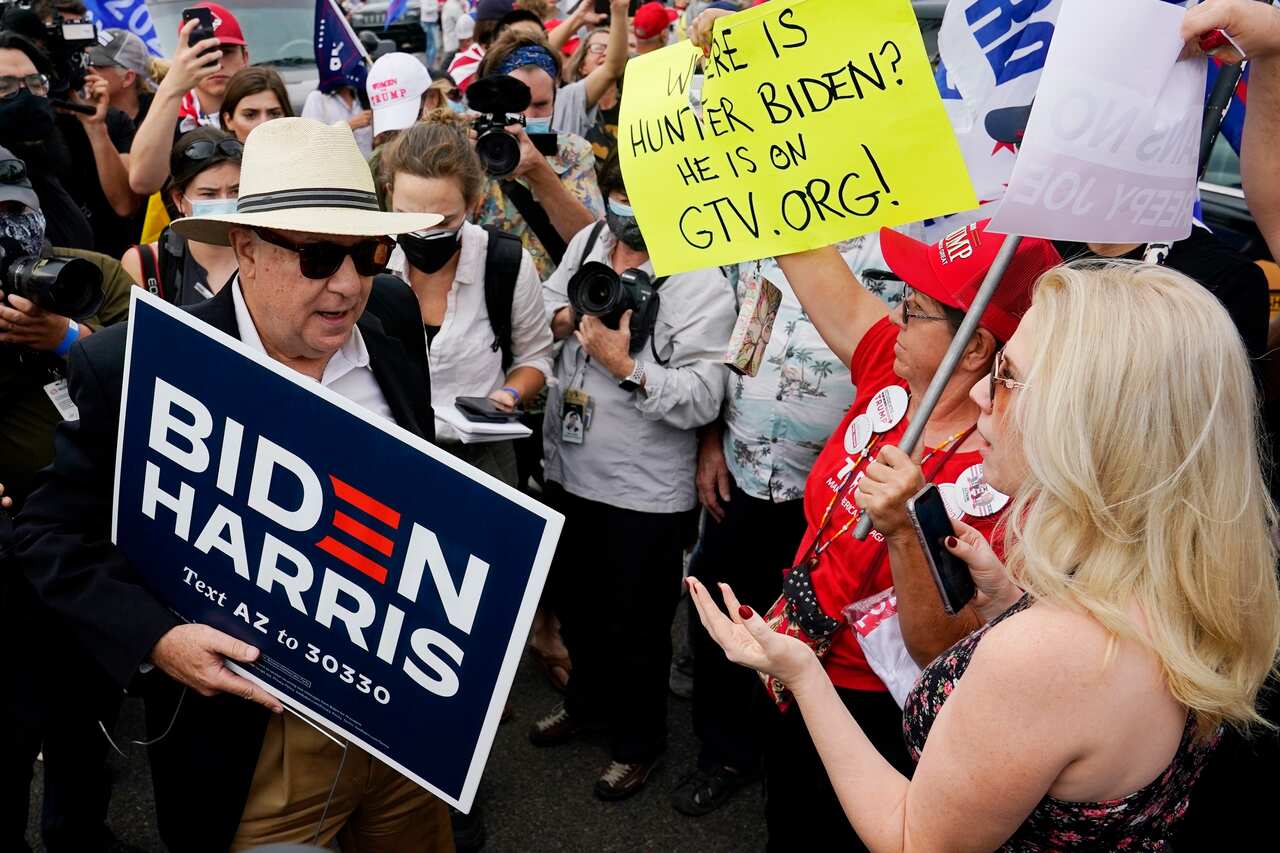 Supporters of President Donald Trump, right, engage a supporter of Democratic presidential candidate Joe Biden, left, at a rally outside the Maricopa County Recorder's Office Friday, Nov. 6, 2020, in Phoenix. (AP Photo/Ross D. Franklin)
