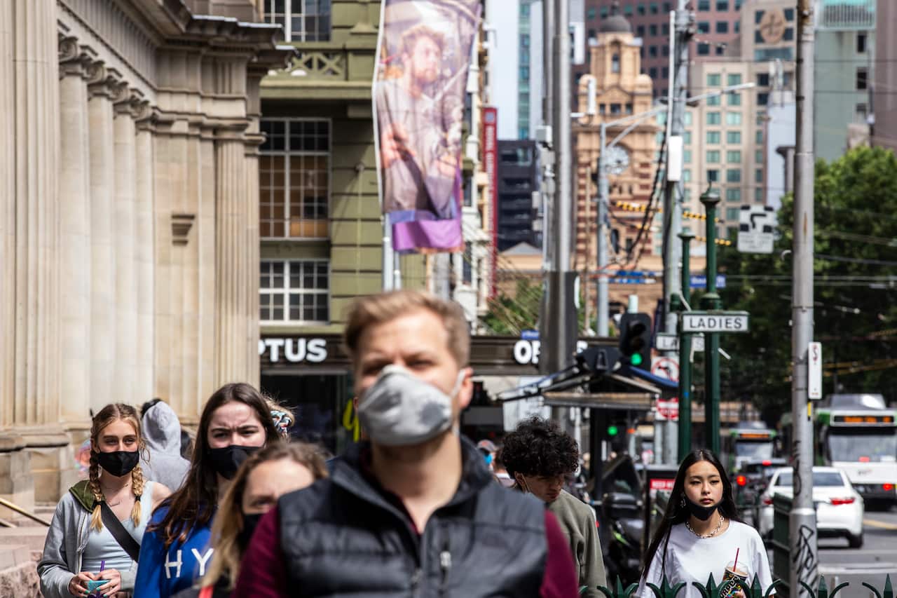 People wearing face masks walk on Elisabeth Street, Melbourne, Victoria.