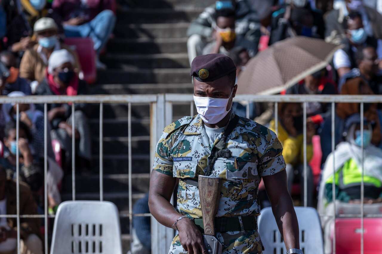 A police officer provides security as Ethiopians wait to give blood at a stadium in the capital Addis Ababa, Ethiopia Thursday, Nov. 12, 2020.