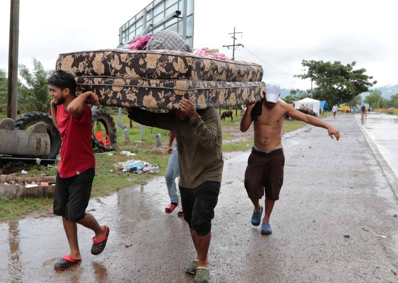 Neighbours help each other as they evacuate the area before Hurricane Iota makes landfall in San Manuel Cortes, Honduras, Monday, November 16, 2020